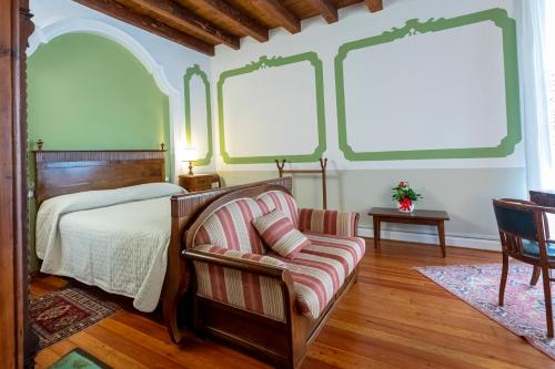 a bedroom with a bed and a chair and windows at Palazzo Scolari in Polcenigo