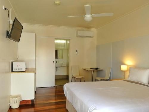a bedroom with a white bed and a table with chairs at Paradise Motel Busselton in Busselton