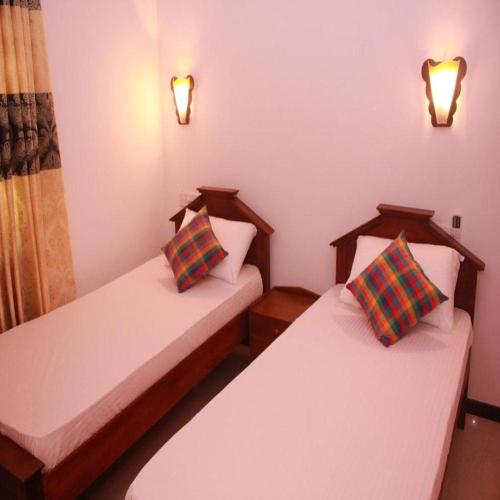 two twin beds in a room with lights on at Villa Koggala in Koggala