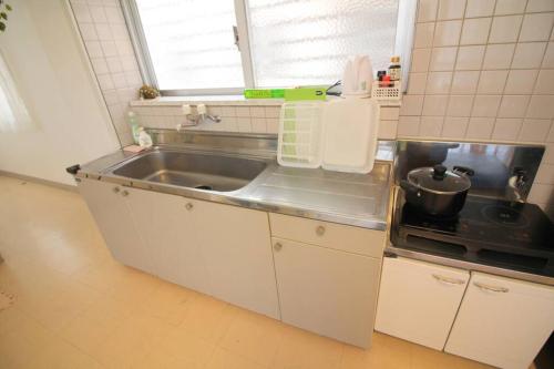 eine kleine Küche mit Spüle und Herd in der Unterkunft 沖縄ライフインゼファー Okinawa Totoro House in Tōbaru