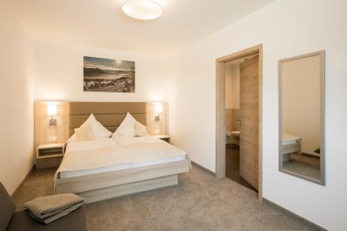 Habitación blanca con cama y espejo en Lieblingsplatz - Willingen inklusive MeineCardPlus, en Willingen