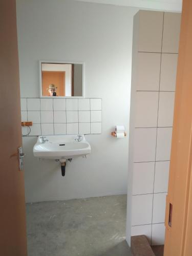 a white bathroom with a sink and a mirror at Old Bridge Camping in Maltahöhe