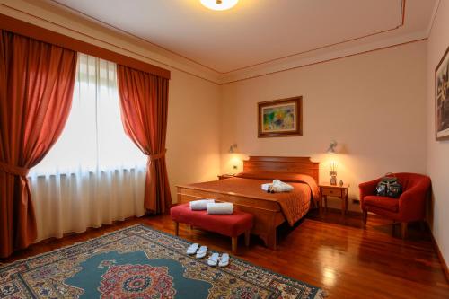 a bedroom with a bed and two chairs and a window at Hotel Rutiliano in Pienza