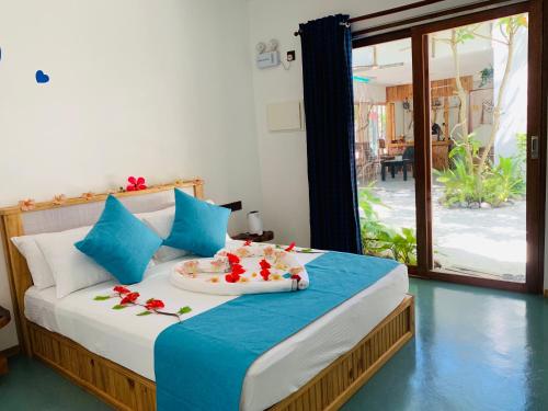 ein Schlafzimmer mit einem Bett und einem Tablett mit Blumen darauf in der Unterkunft Ithaa Thoddoo Inn in Thoddoo-Atoll