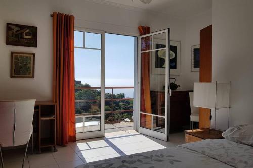 1 dormitorio con una gran puerta de cristal que da a un balcón en Raposeira de São João, the feeling of peace, space and quiet, Whole villa is yours, en Fajã da Ovelha