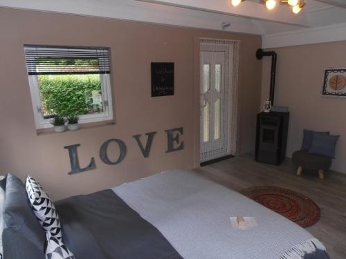 1 dormitorio con 1 cama con la palabra amor en la pared en Gastenverblijf 't Achterhoes, en Bellingwolde