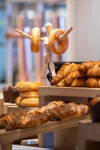 a person holding a donut and a bunch of pastries at INNSiDE by Meliá Zaragoza in Zaragoza