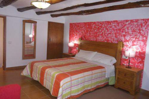 1 dormitorio con cama y pared roja en Casa Rural La Buhardilla, en Las Cuevas de Cañart