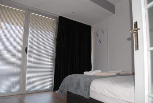 a bedroom with a bed and a window with blinds at Stan na dan - apartman Djordjevic in Vranje