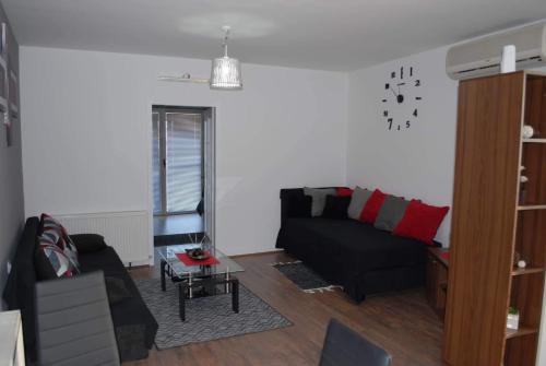 a living room with a black couch and a table at Stan na dan - apartman Djordjevic in Vranje