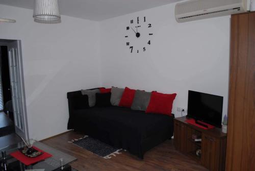 a living room with a couch and a clock on the wall at Stan na dan - apartman Djordjevic in Vranje