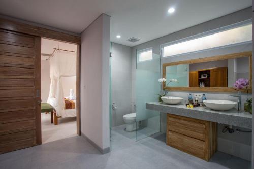 a bathroom with two sinks and a toilet and a mirror at The Awandari Villas Seminyak - CHSE Certified in Seminyak