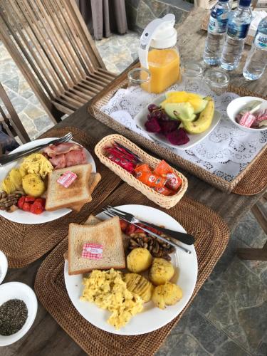 a table with plates of breakfast food on it at Batur Sunrise Guesthouse in Kintamani