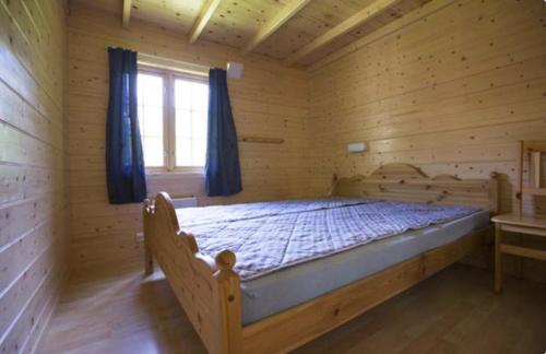 ein großes Bett in einem Holzzimmer mit Fenster in der Unterkunft Trollveggen Camping in Åndalsnes