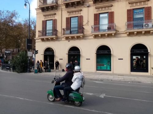 a woman and a child riding a scooter down a street at Ariston Petit Hotel in Palermo