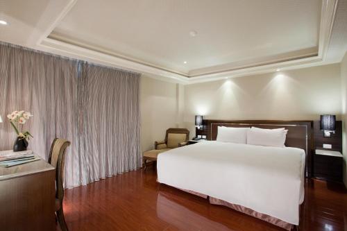 a bedroom with a large white bed and a desk at Deja Vu Hotel in Taipei