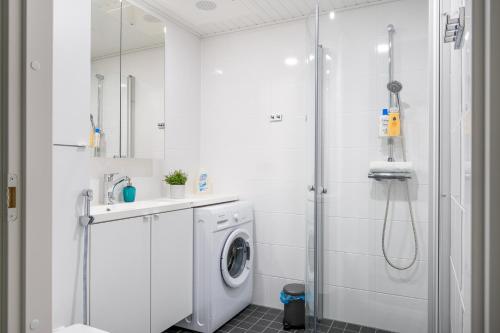 a white bathroom with a washing machine and a shower at Hiisi Homes Vantaa Kaivoksela in Vantaa