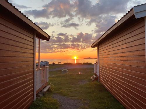 a sunset over the ocean between two buildings at Ramberg Gjestegård in Ramberg