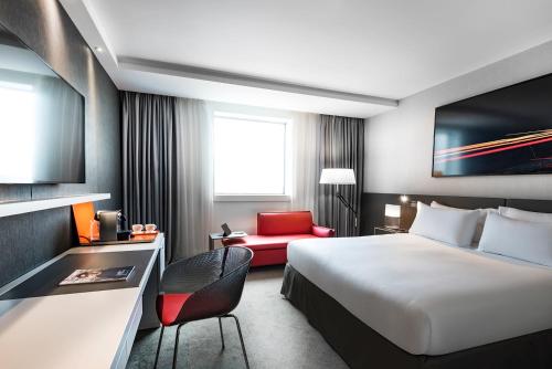 a hotel room with a bed and a red chair at Pullman Paris La Défense in Courbevoie