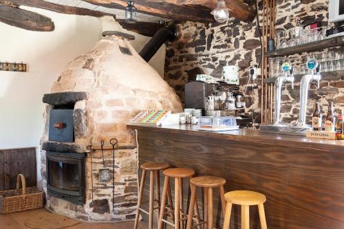- un bar avec un four à pizza dans une pièce avec des tabourets dans l'établissement La Rosa del Agua, à El Acebo de San Miguel