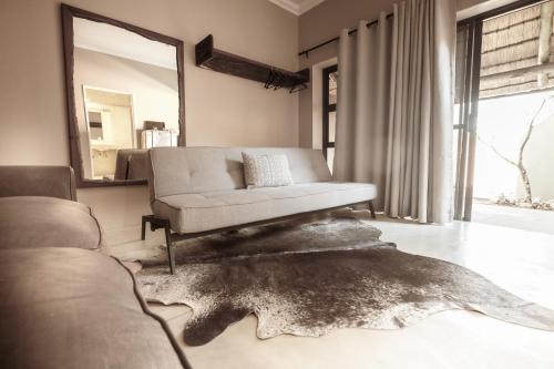 a living room with a couch and a mirror at Bagatelle Kalahari Game Ranch in Hardap