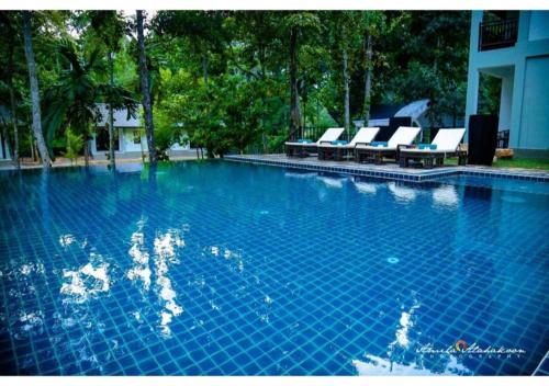 a large swimming pool with lounge chairs in a building at Serendib Signature Resort in Digana