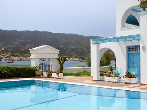 a swimming pool in front of a building with a house at Nikis Village in Poros