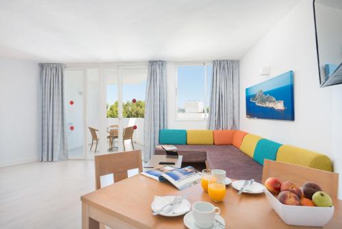 ein Wohnzimmer mit einem Tisch und einem Sofa in der Unterkunft Aparthotel Ses Fotges in Playa de Muro