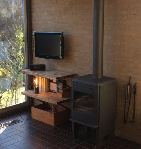 a fireplace in a living room with a television and a stove at Bungalow 221 in Noordwijkerhout