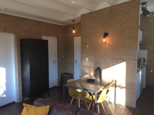 a living room with a table and yellow chairs at Bungalow 221 in Noordwijkerhout