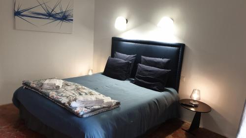 Schlafzimmer mit einem Bett mit blauer Bettwäsche und Kissen in der Unterkunft la bastide de l'adrech in Manosque