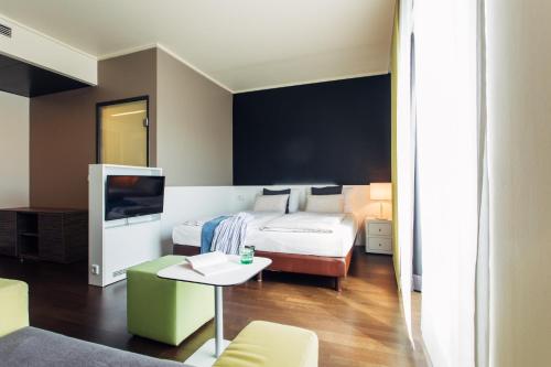 a bedroom with a bed and a table and a tv at harry's home hotel & apartments in Linz