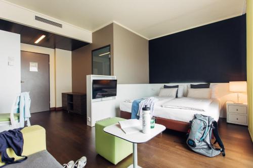 a bedroom with a bed and a table and a tv at harry's home Linz-Urfahr hotel & apartments in Linz