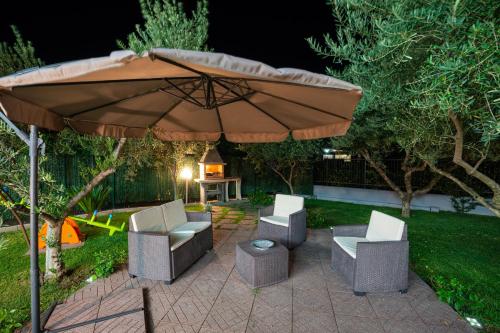 an umbrella and chairs on a patio at night at Arcobaleno Apartment in Fondi