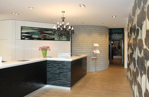 a lobby with a counter and a chandelier at Sporthotel Racket Inn in Hamburg