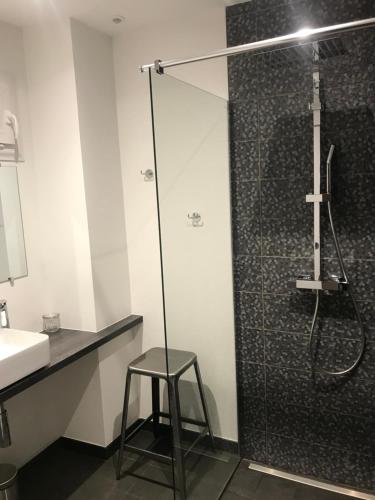 a bathroom with a shower with a stool next to a sink at Augustodun'Home in Autun