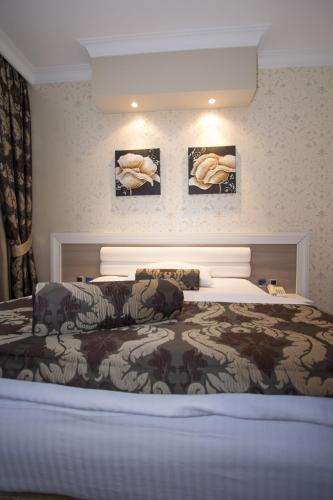 a bed in a bedroom with pictures on the wall at Hotel Talija in Banja Luka