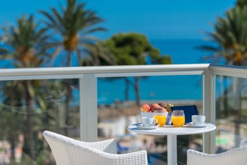 einen Tisch mit Obst und Getränken auf einem Balkon mit Strandblick in der Unterkunft Aparthotel Ses Fotges in Playa de Muro