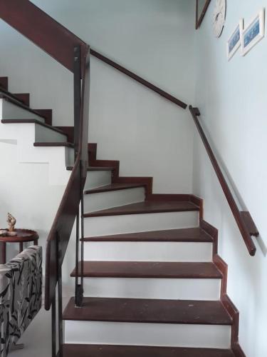a staircase with wooden railings and white walls at Casa Perfeita para suas férias in Salinópolis
