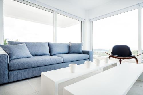 a living room with a blue couch and a table at Villa Arete by PosarelliVillas in Perítheia