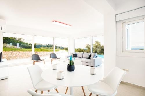 a white living room with a white table and chairs at Villa Arete by PosarelliVillas in Perítheia