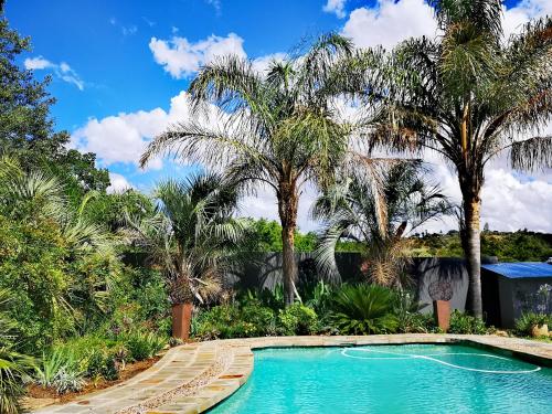 a swimming pool in a resort with palm trees at INBLOEM in Bloemfontein