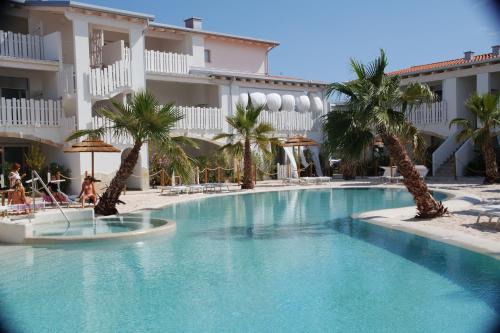 une piscine avec des palmiers en face d'un hôtel dans l'établissement Cala Blu Residence con piscina-Centralissimo Lido di Jesolo, à Lido di Jesolo