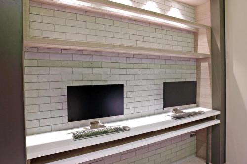 a brick wall with two computer monitors on a shelf at KIWI SHARE HOTEL ZHONGLI in Zhongli