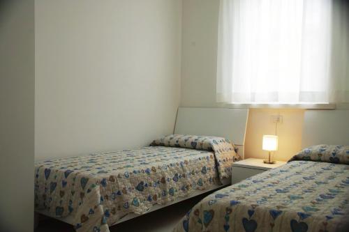 two beds in a small room with a window at Cala Blu Residence con piscina-Centralissimo Lido di Jesolo in Lido di Jesolo