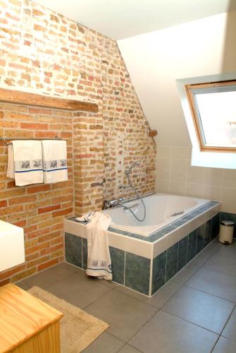 a bathroom with a bath tub with a brick wall at Holiday Home De Colve in Bruges