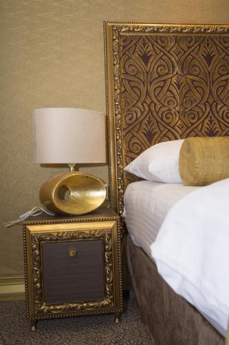 a bed with a gold frame and a lamp on a night stand at Hotel Talija in Banja Luka