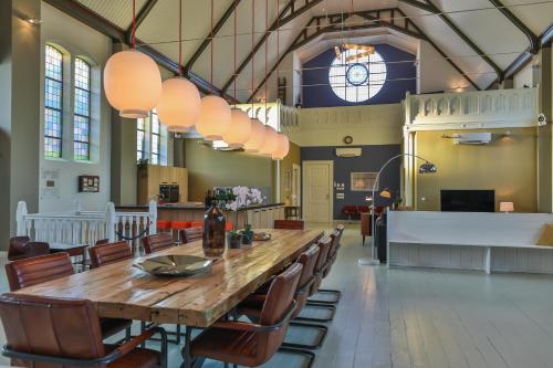a large dining room with a wooden table and chairs at Church conversion for a unique stay and experience in Rinsumageest
