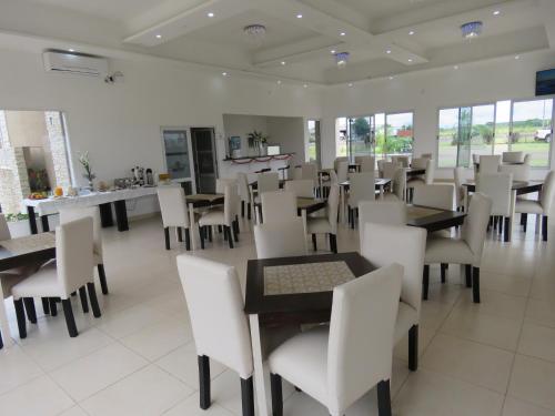 a dining room with tables and white chairs at GRAN HOTEL CURUZU CUATIA in Curuzú Cuatiá