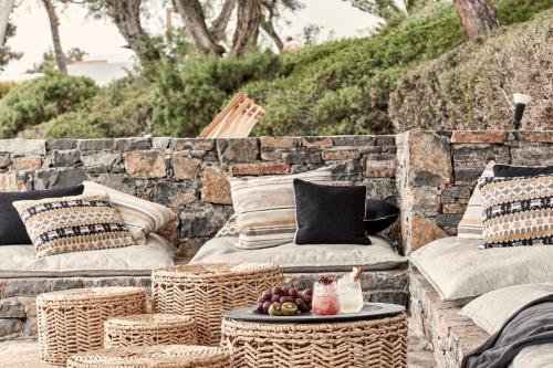 a patio with wicker chairs and a table with fruit on it at Minos Beach Art Hotel, a Member of Design Hotels in Agios Nikolaos